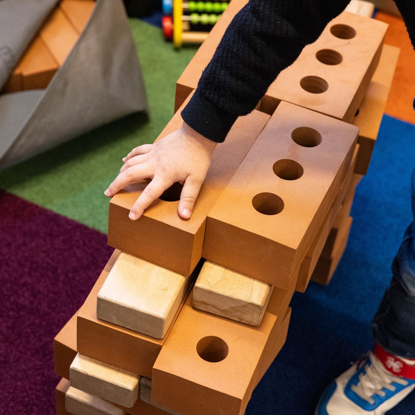 Child's hand building wall with bricks