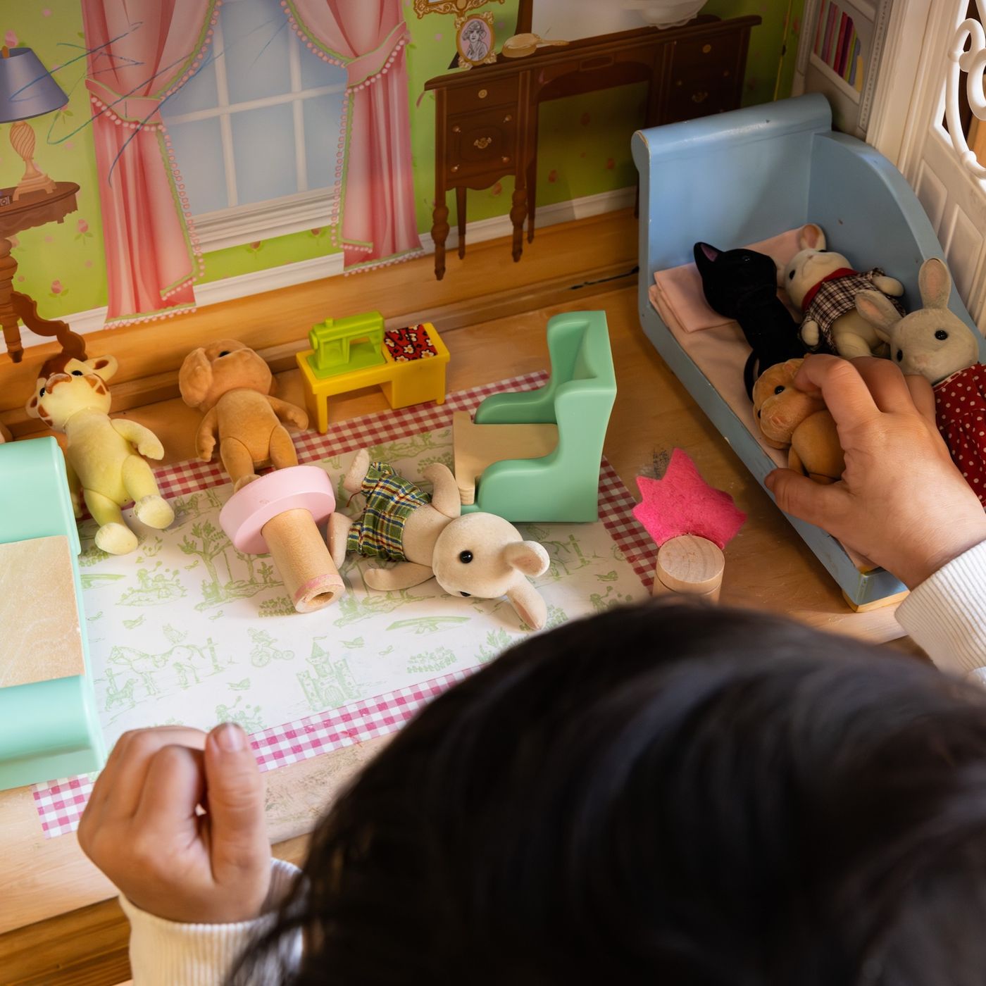 Girl playing with animals in doll's house