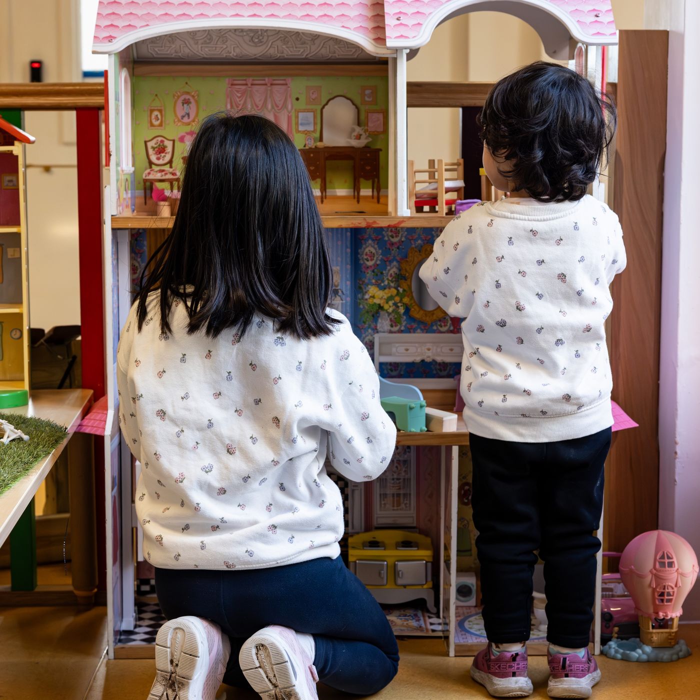Two children playing with dolls' house