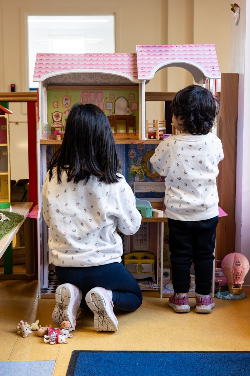 Two children playing with dolls' house