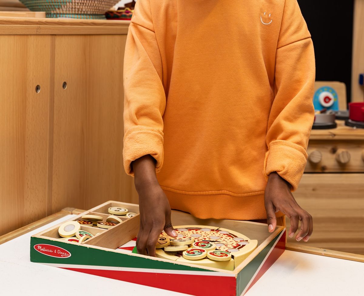 Hands playing with toy pizza
