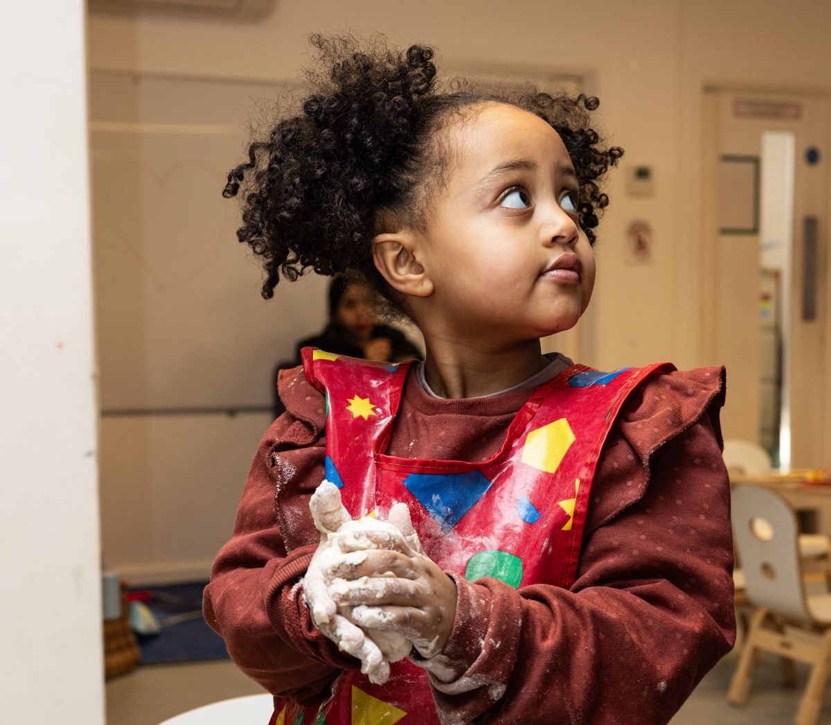 Girl with playdough in apron