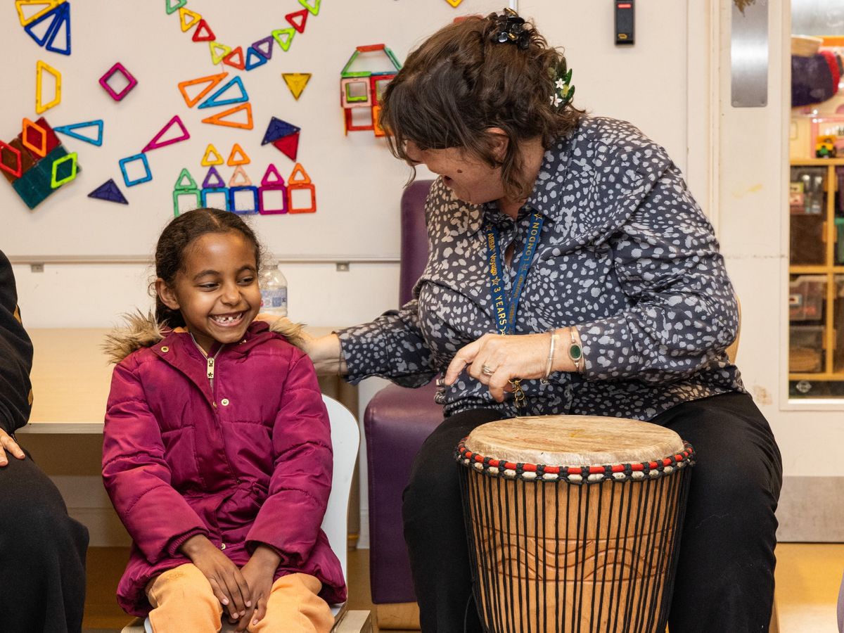 Staff playing drum with young child
