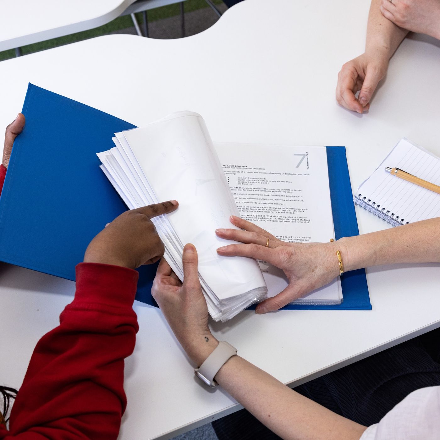 Three people looking at work in a folder